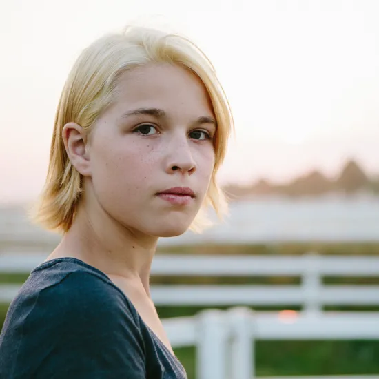 Ein junger Mensch mit blonden Haaren schaut in die Kamera