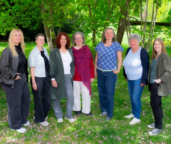 Das Team von Wildwasser Wetterau steht im Halbkreis in sommerlicher Kulisse aus Wiese und Bäumen.