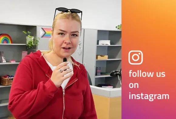 Eine junge Person steht, den Betrachtenden zugewandt, in einem Empfangsbereich und spricht in ein Mikrofon. Rechts daneben auf einer Fläche: die Logo-Grafik von instagram.